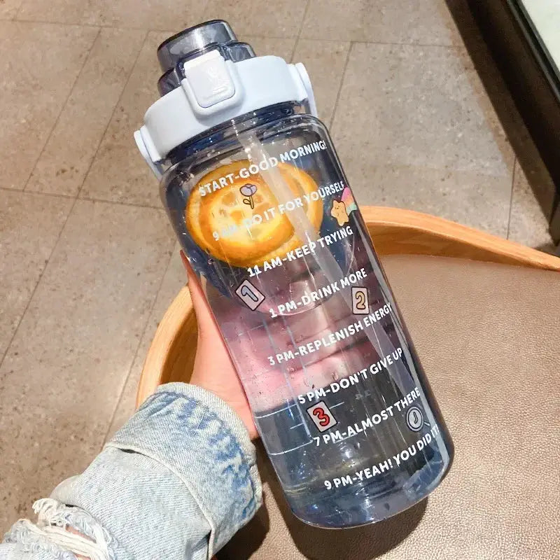 Clear blue 2L fitness jug with straw, motivational time markers, and fruit infuser, ideal for daily hydration and energy replenishment.