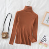 Orange women's turtleneck sweater on bed