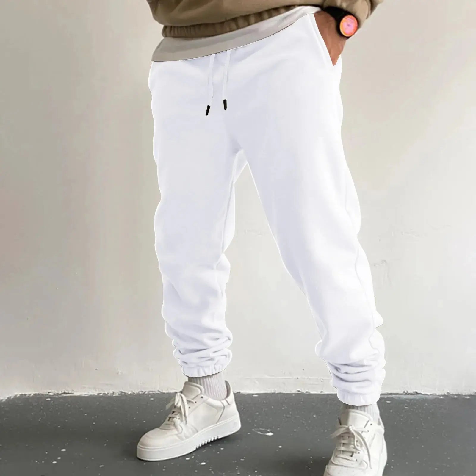 Men’s white jogger sweatpants featuring a high waist drawstring and side pockets, loose fit design for casual or sportswear, worn with white shoes.