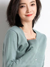 Woman in green cardigan with a gentle smile.