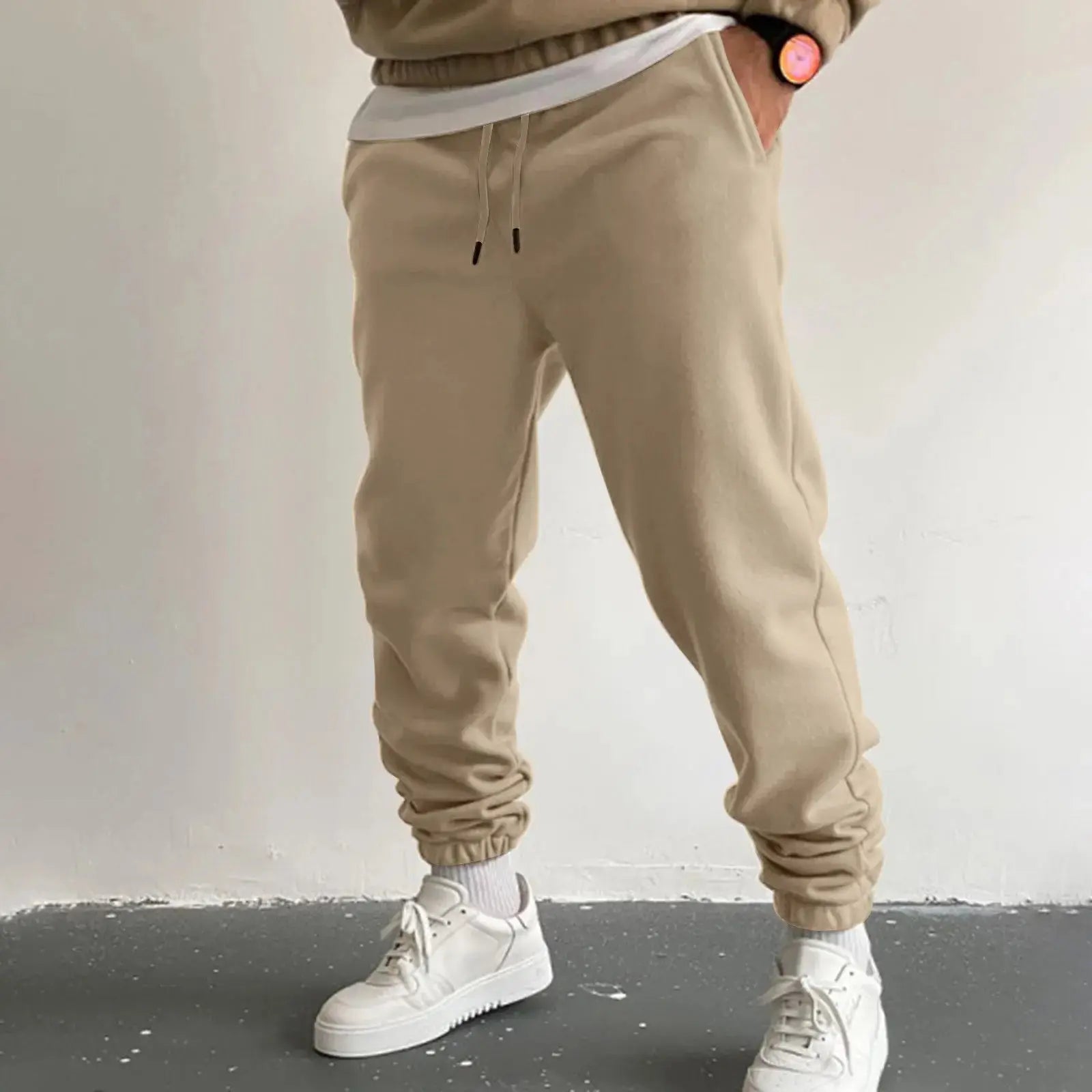 Men’s beige jogger sweatpants with high waist drawstring and side pockets, relaxed fit trousers for casual wear or workouts, styled with white sneakers.