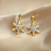 Gold snowflake dangle earrings on satin fabric