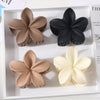 Pastel flower hair clips on wooden surface