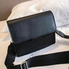 Black faux leather crossbody bag on bed