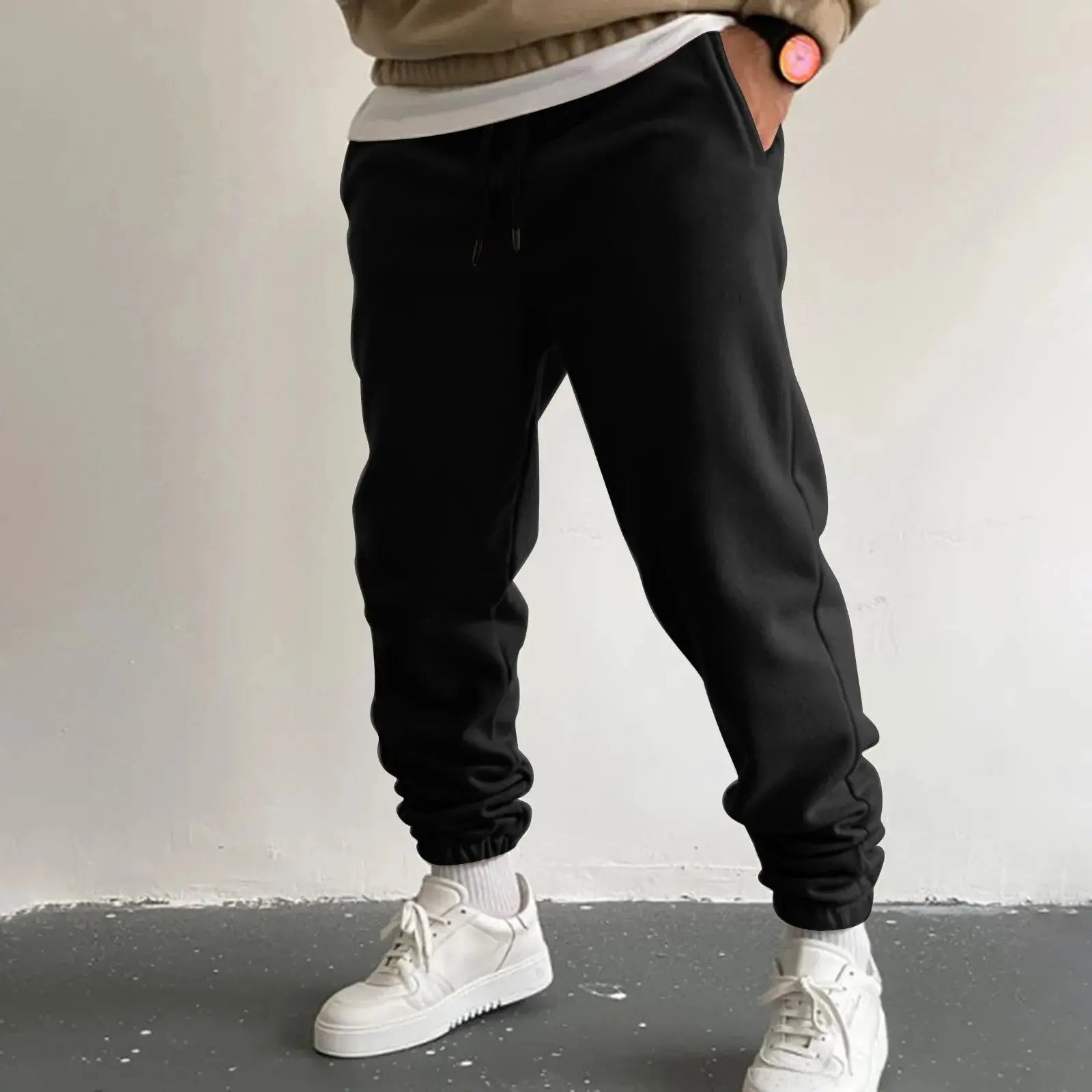 Men’s black jogger sweatpants with high waist drawstring and pockets, loose fit trousers ideal for casual wear or running, styled with white sneakers.