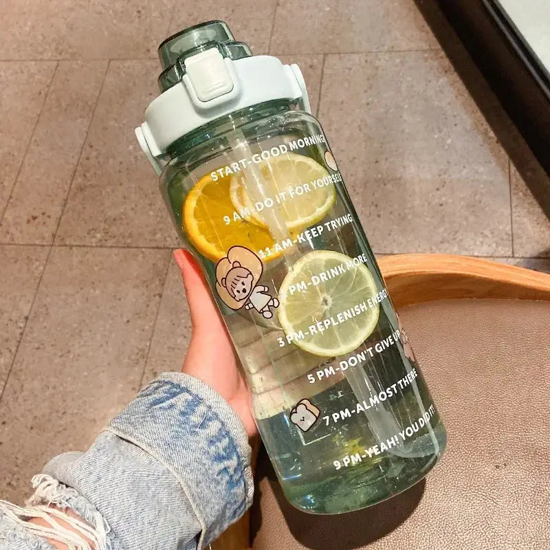 Green 2L sports water bottle with straw and time marker, decorated with bear stickers and lemon slices for summer hydration and fitness use.