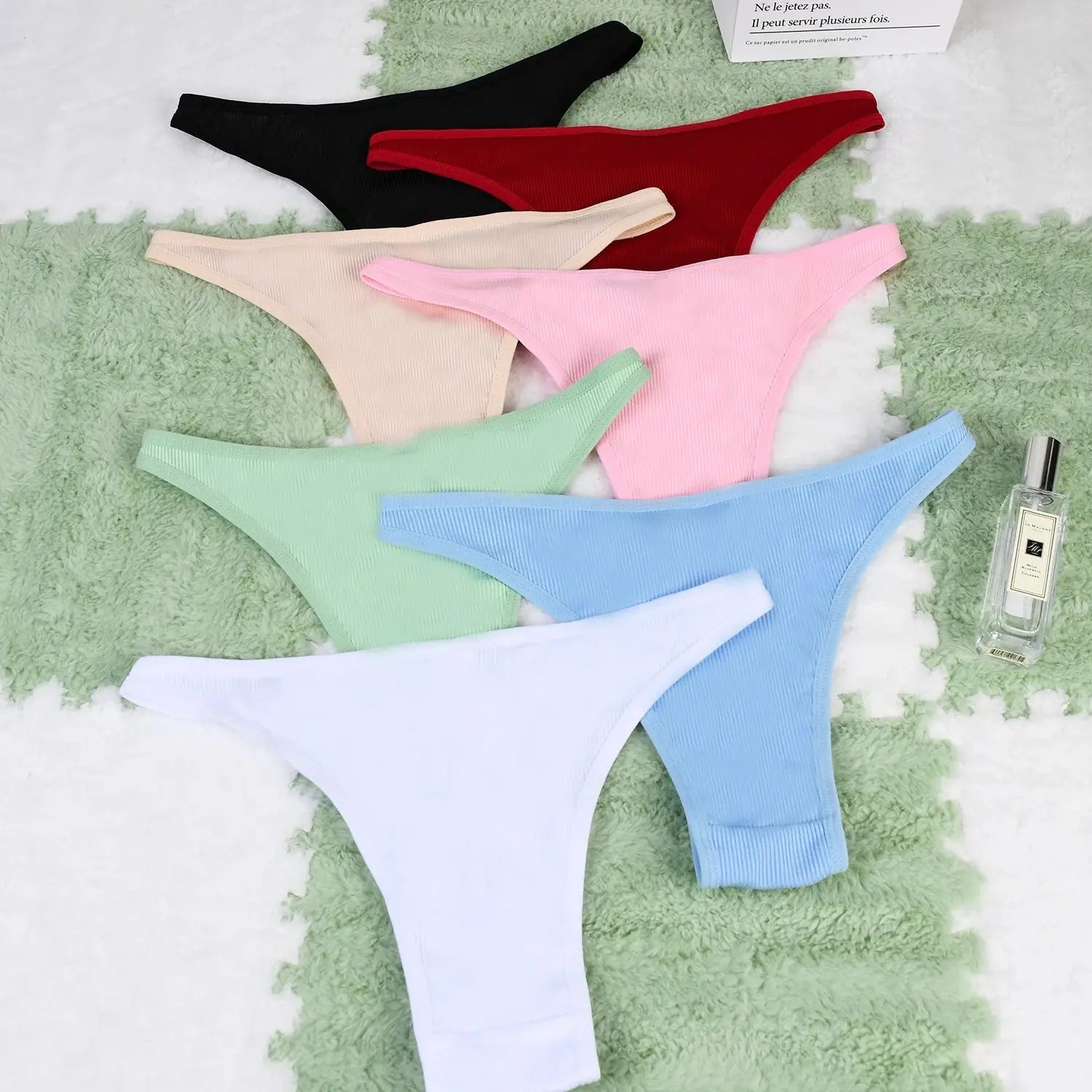 Back view of 7-piece ribbed cotton thong set in pastel and bold colors, seamless low-rise design for women’s everyday comfort.