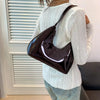 Glossy dark brown shoulder bag worn by person