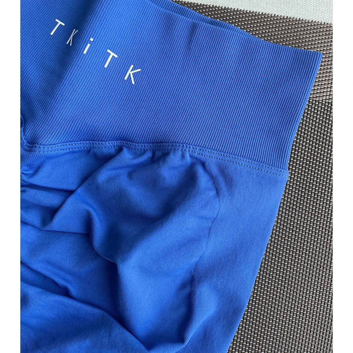 Close-up of blue seamless compression shorts from Women's 2-Piece Seamless Workout Set, featuring ribbed waistband and TKITK logo. Ideal for gym and yoga.