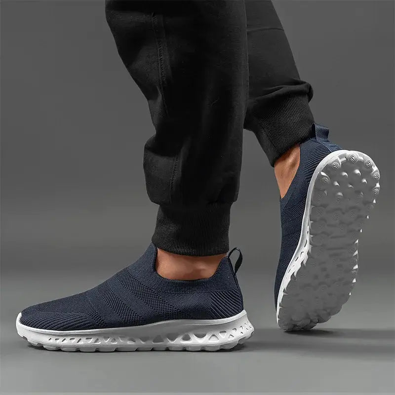 Side and sole view of navy men’s slip-on sneakers with lightweight mesh and textured grip, perfect for athletic and casual use.