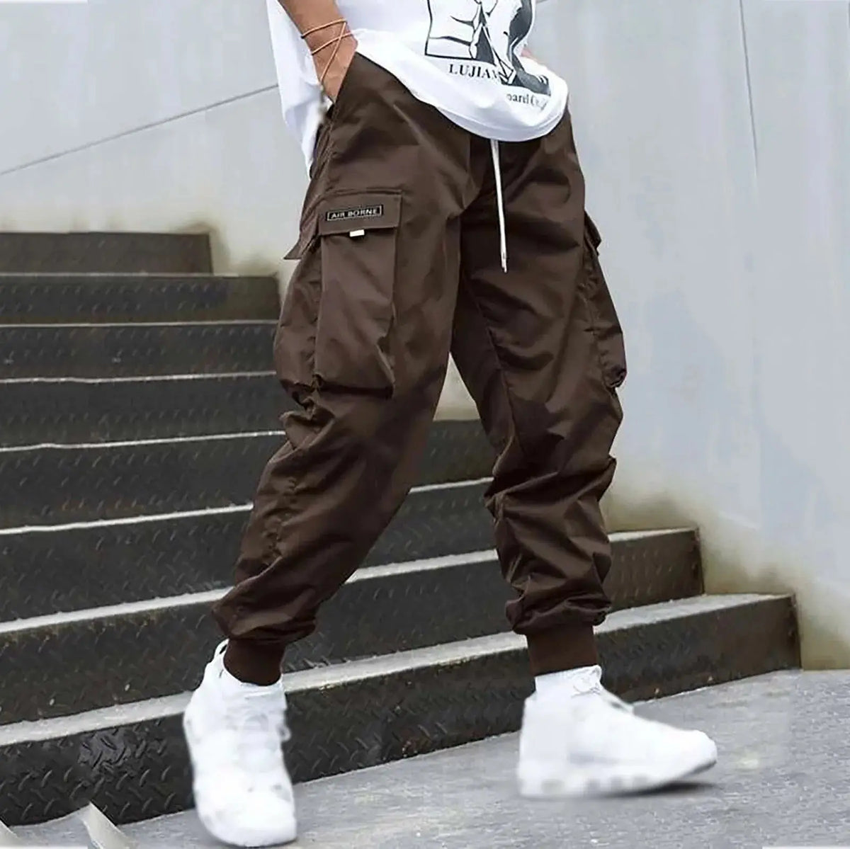 Brown men’s casual cargo jogger pants with drawstring and flap pockets, offering a rugged look for streetwear or daily use.