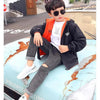 Child in black and orange jacket sitting on car