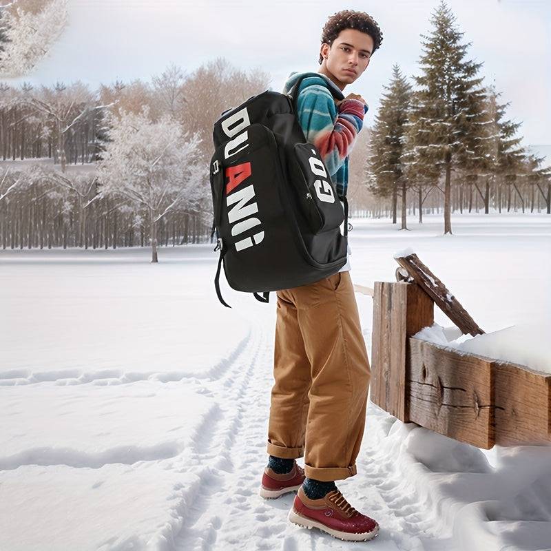 Man outdoors in snow carrying black large travel backpack with DUANI print, ideal for winter travel and outdoor adventures.