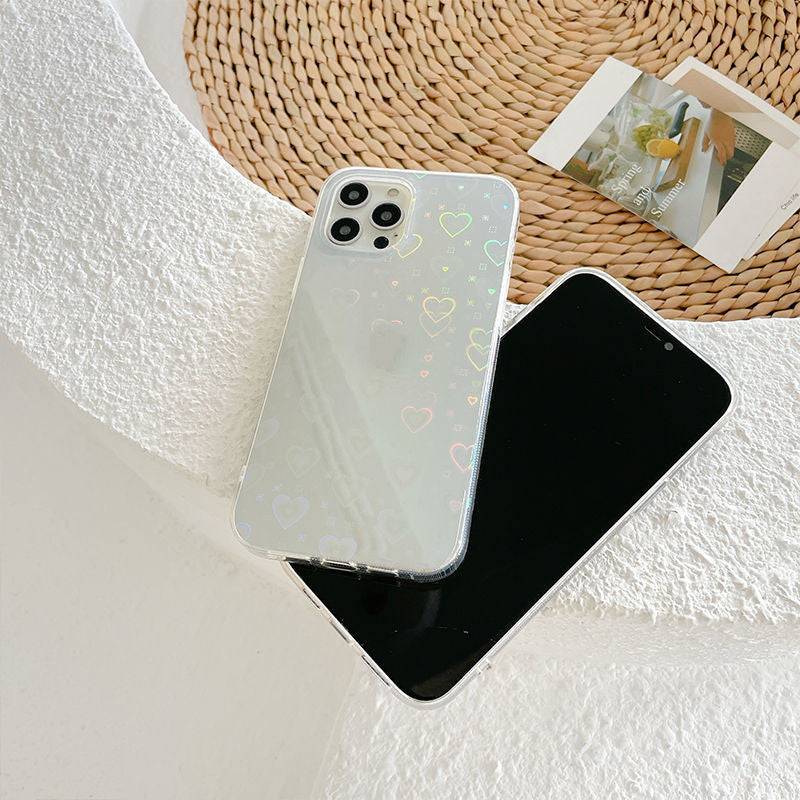 Clear silicone phone case with laser colorful heart design, shown with smartphone on a textured surface, ideal for stylish and protective use.
