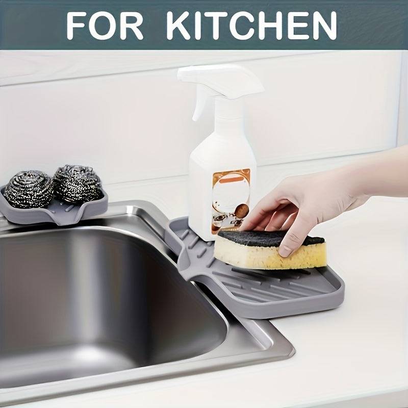 Multi-purpose silicone sink tray used in kitchen for holding sponge, steel wool, and spray bottle, fits neatly on countertop edge.