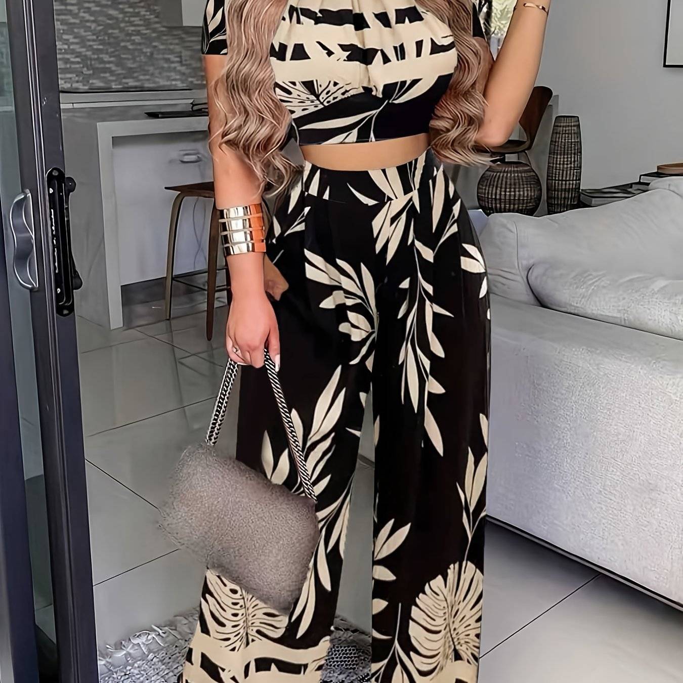 Chic Women's 2-Piece Leaf Print Summer Set styled with accessories, featuring a round-neck top and wide-leg pants in a bold black and beige print.